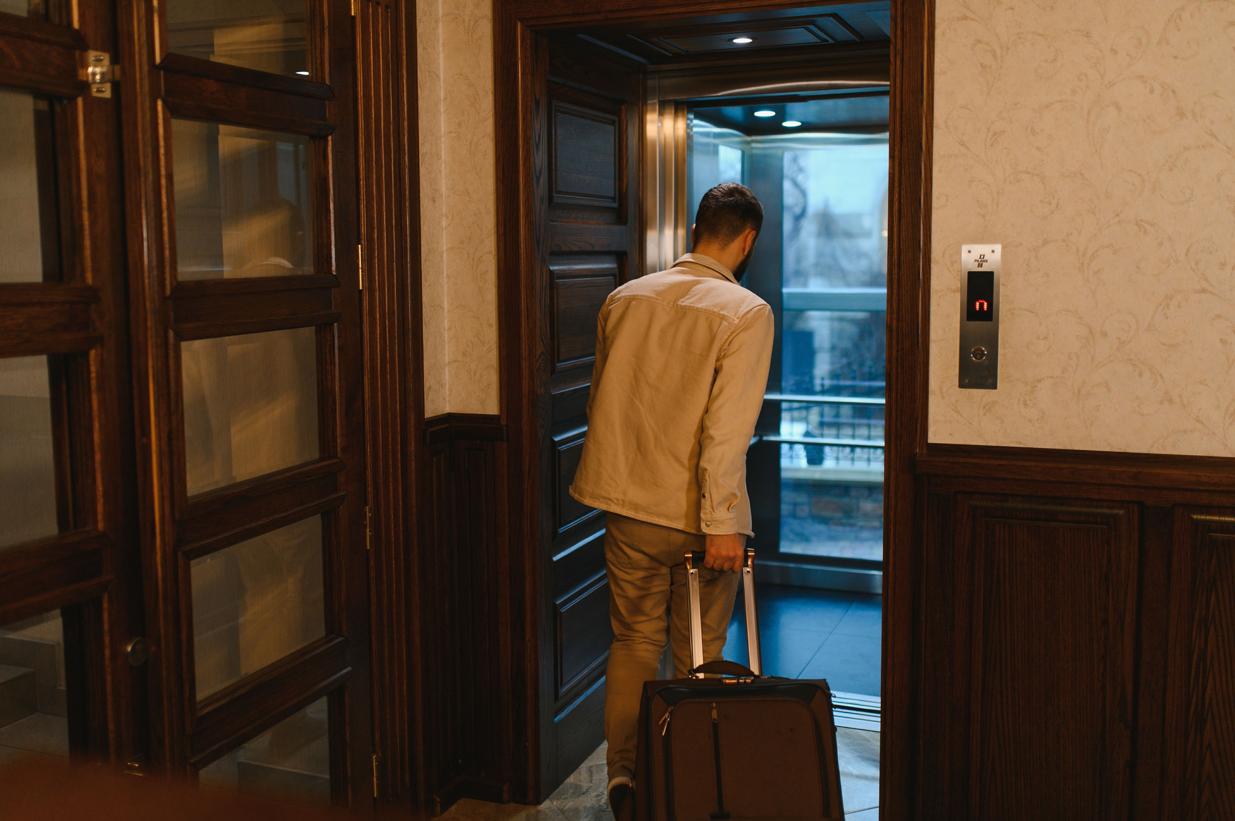 Man with travel luggage entering a modern hotel elevator, preparing for his trip or leaving after his stay