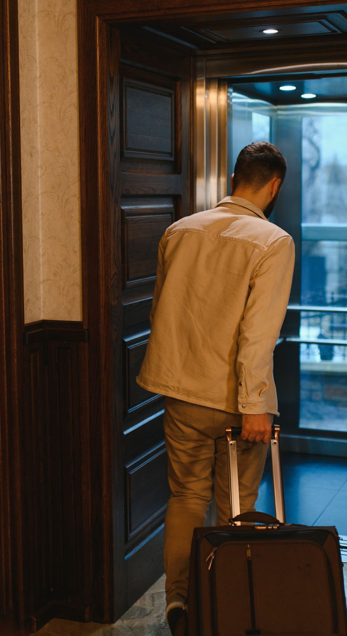 Man with travel luggage entering a modern hotel elevator, preparing for his trip or leaving after his stay